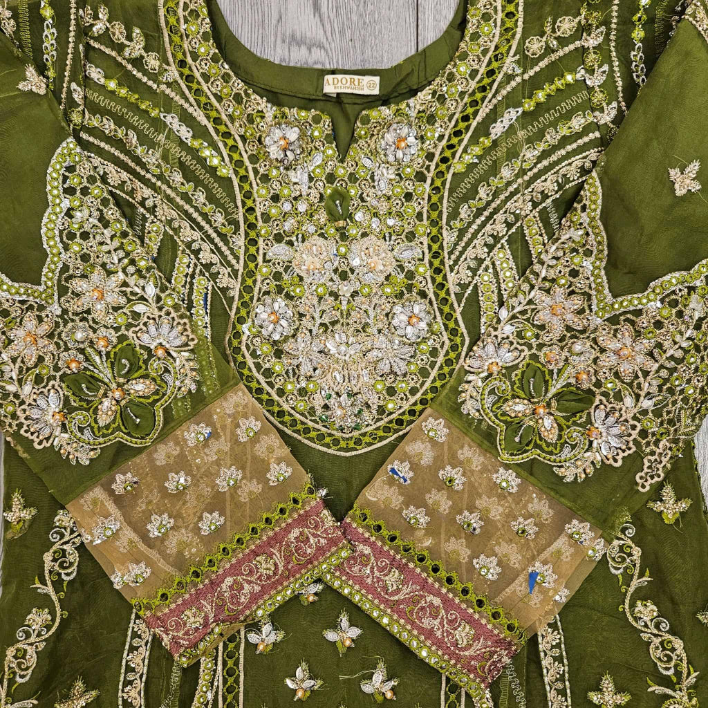 Green embroidered garment with intricate patterns and a visible brand label.