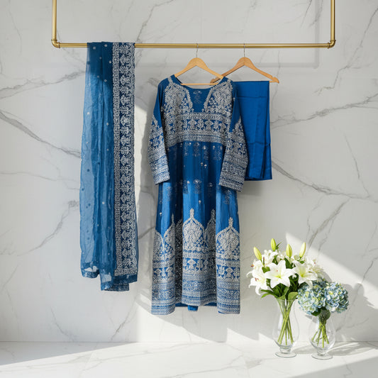 Blue embroidered outfit on a hanger against a patterned wall.